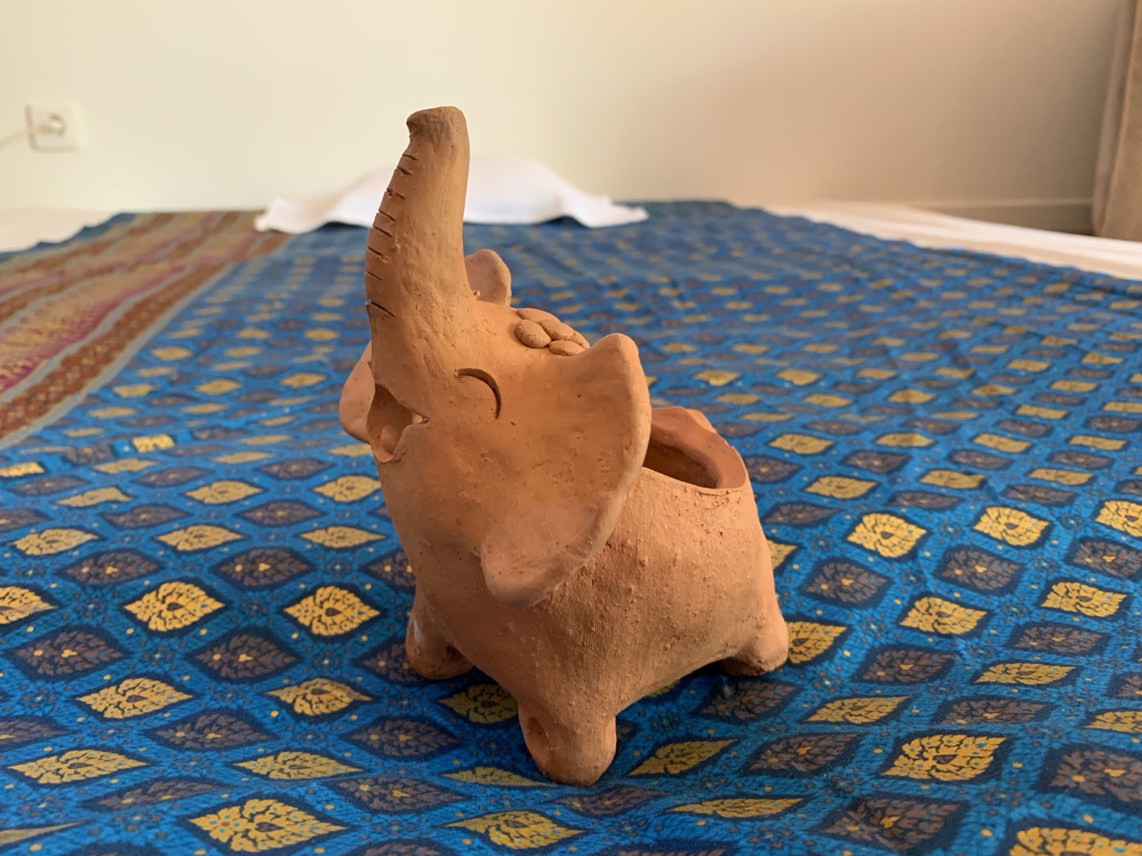 Le petit éléphant en terre cuite rapporté de Thaïlande, posé sur le tissu du futon