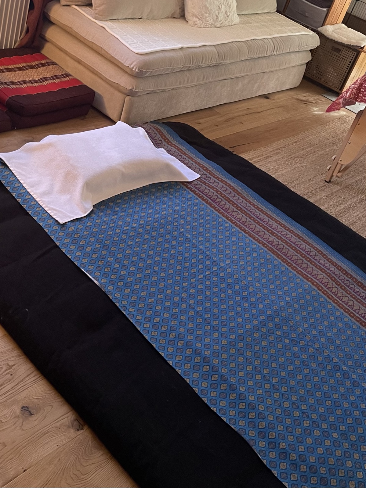 Le futon du cabinet, recouvert de son tissu thaïlandais bleu et de son linge blanc